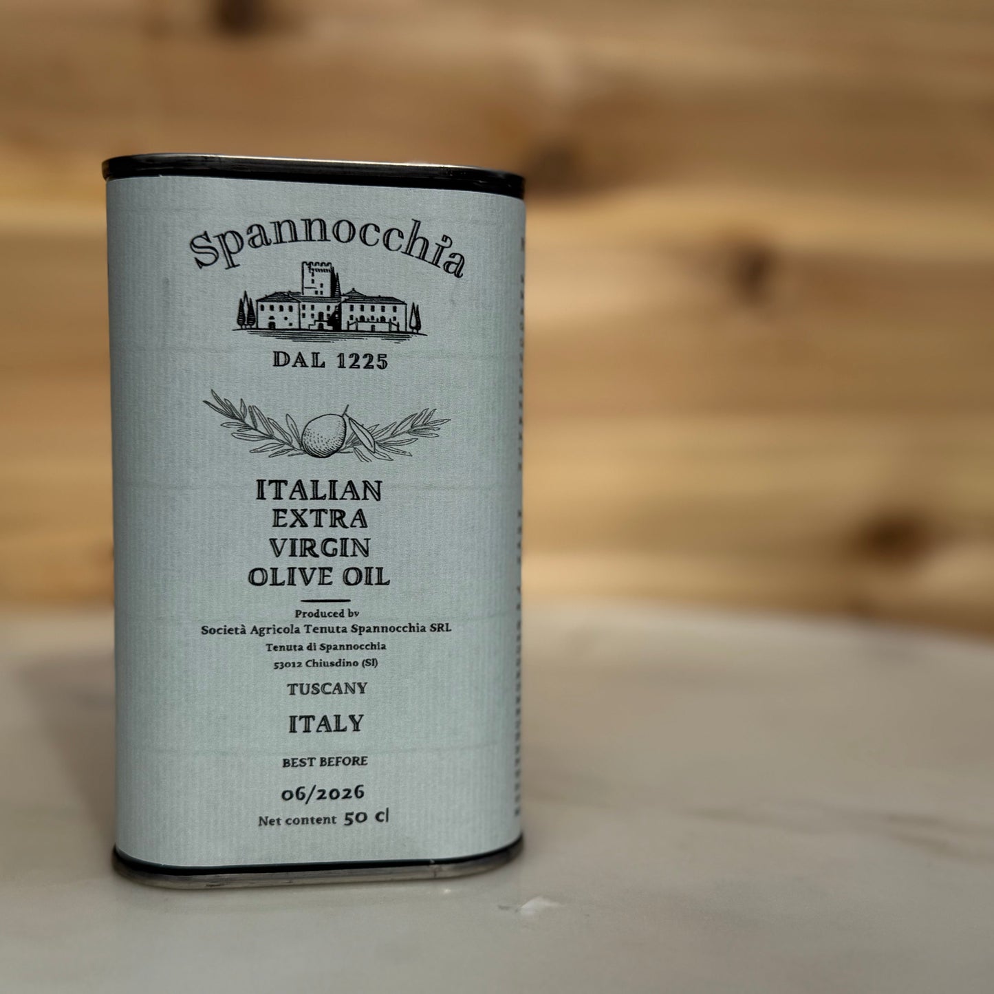One 500ml can of olive oil on a white marble surface with a wood background out of focus.