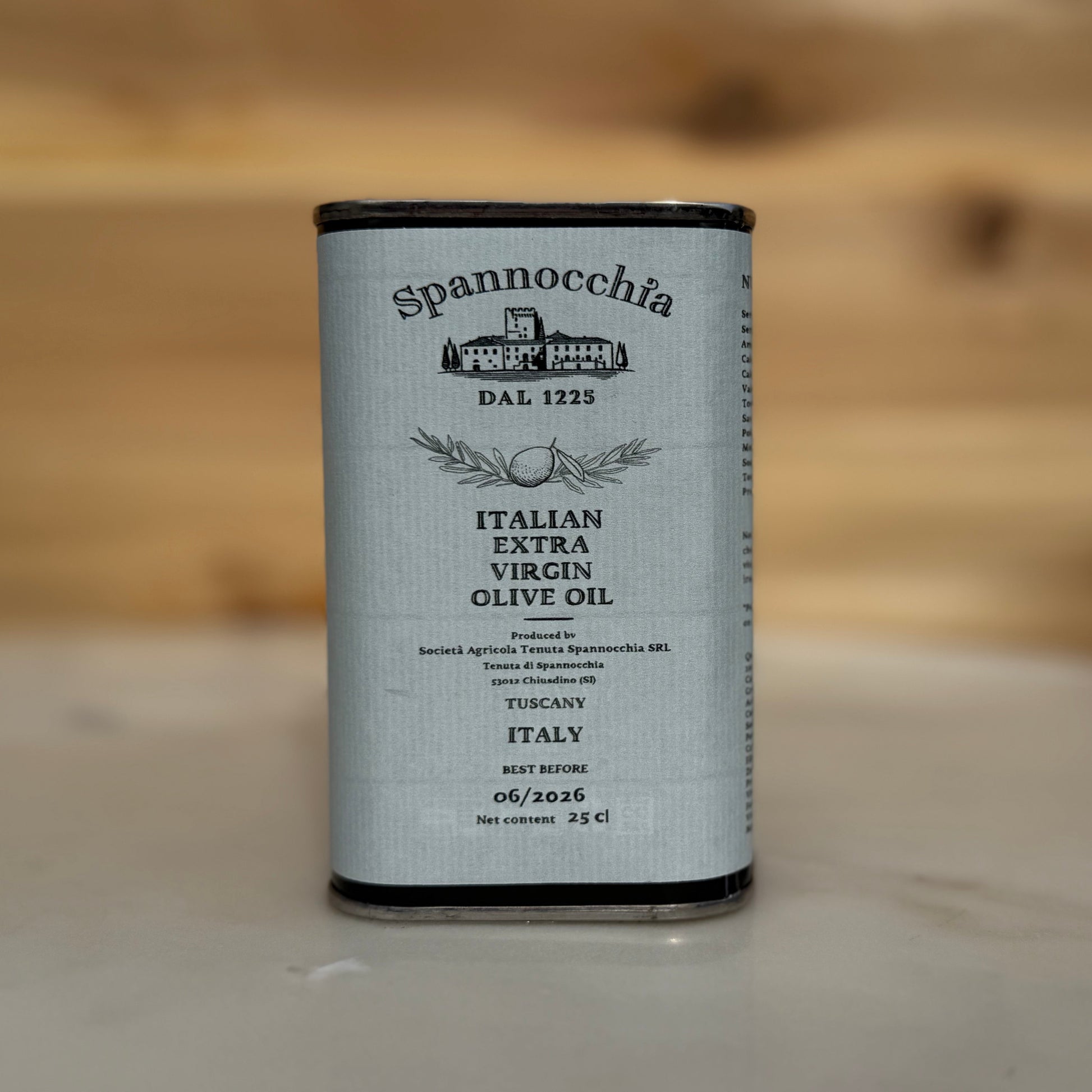 One 250ml can of olive oil on a white marble surface with a wood background out of focus.