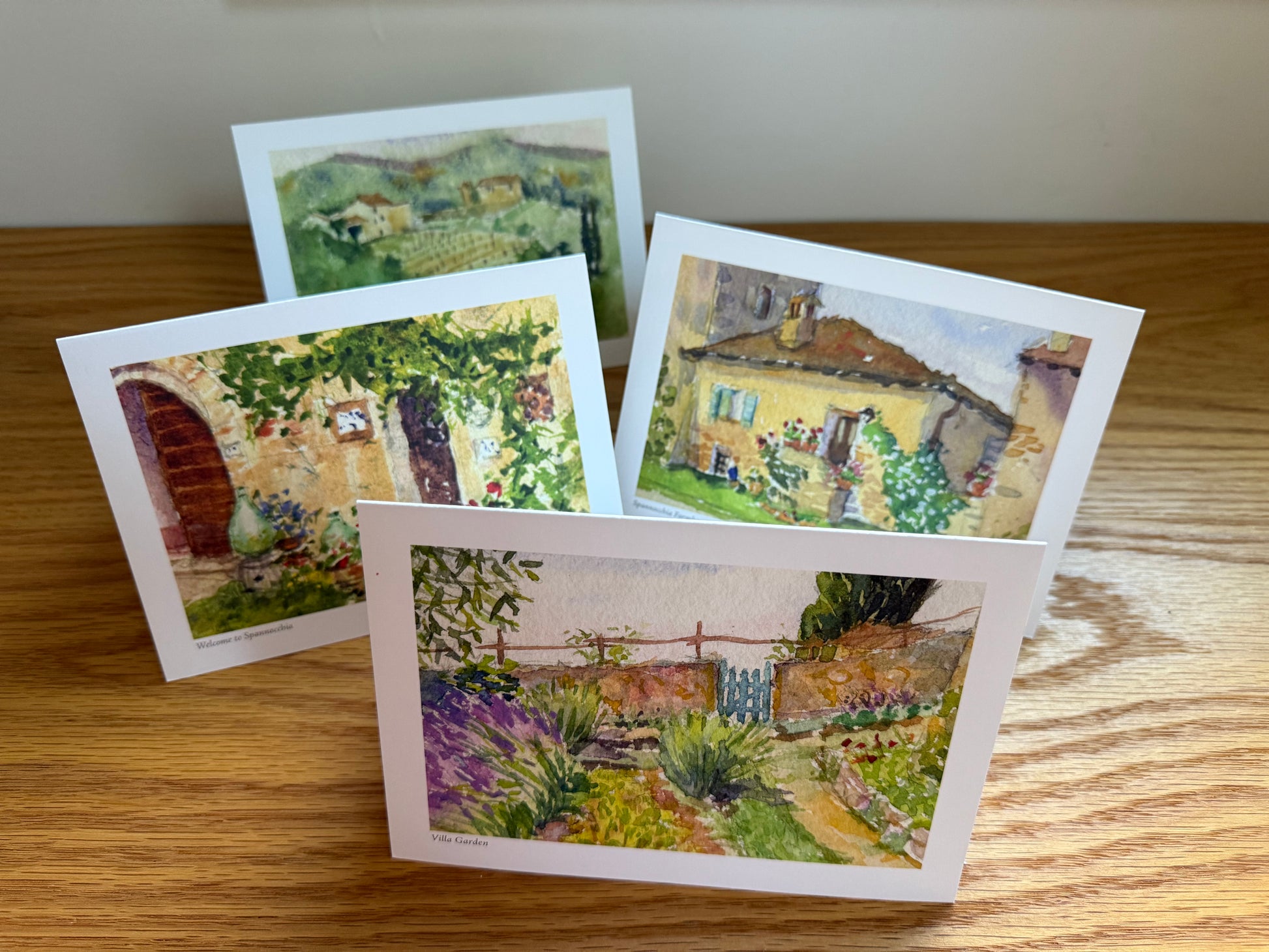 Set of four notecards, upright on a wooden surface.