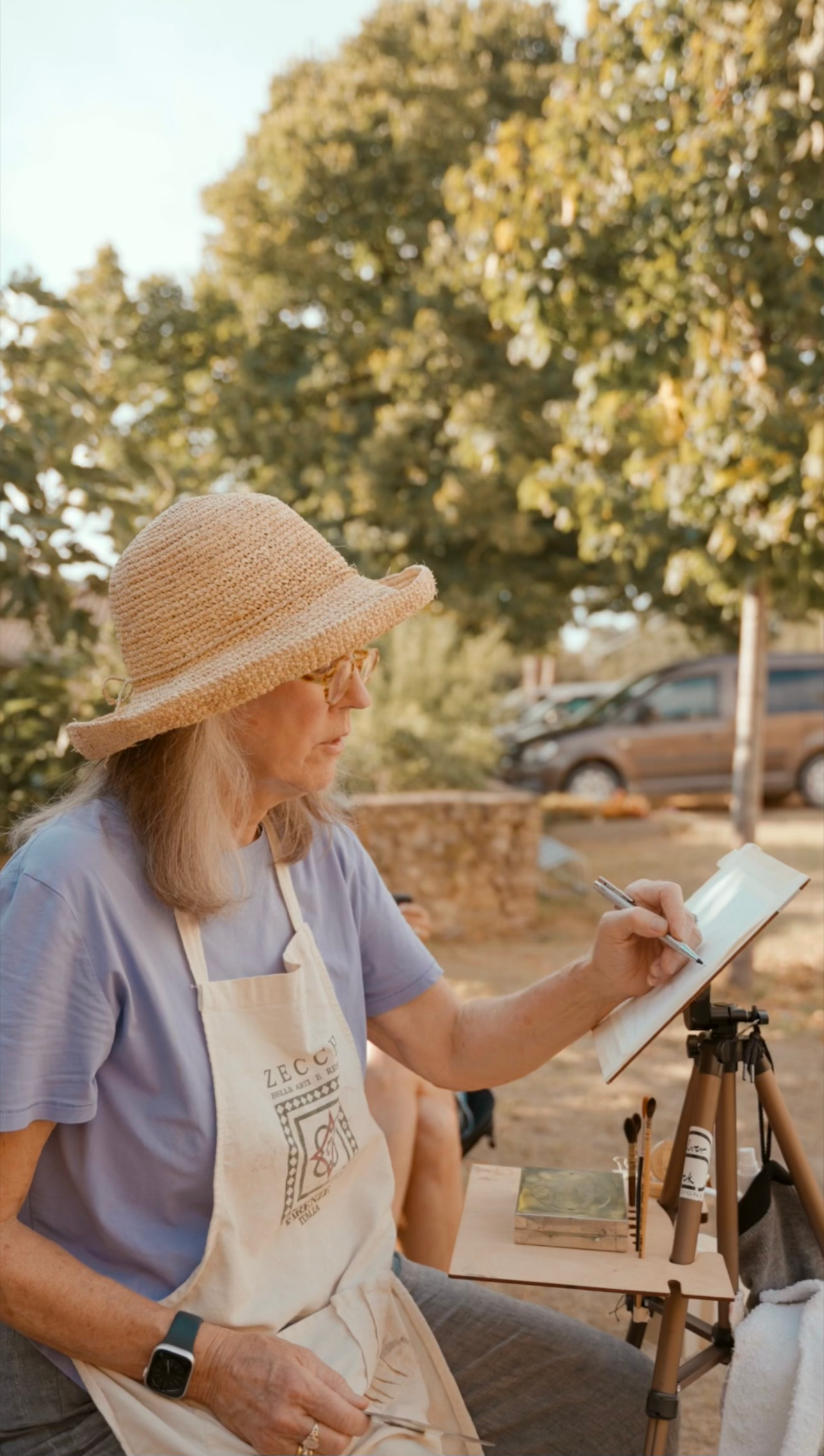 Linda Warnere Constantino in profile, painting outside in the courtyard at Spannocchia.