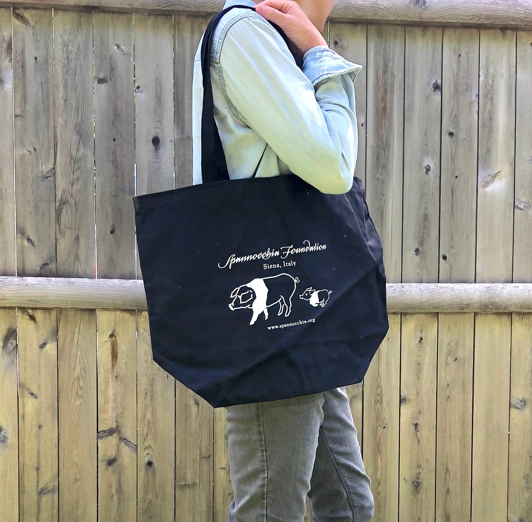 Person holding black Spannocchia Foundation tote